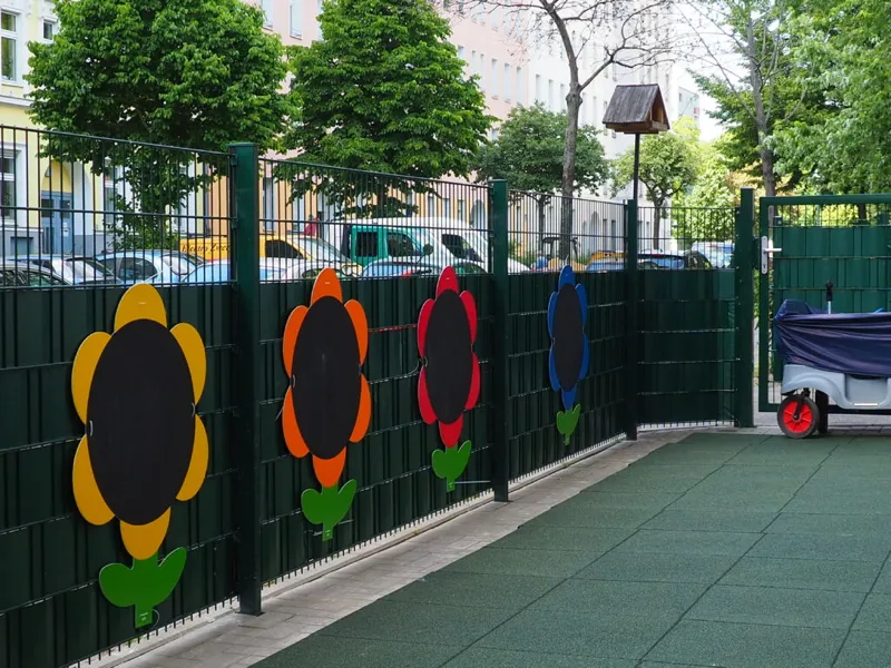 Außenbereich mit bunten Blumen-Tafeln am Zaun